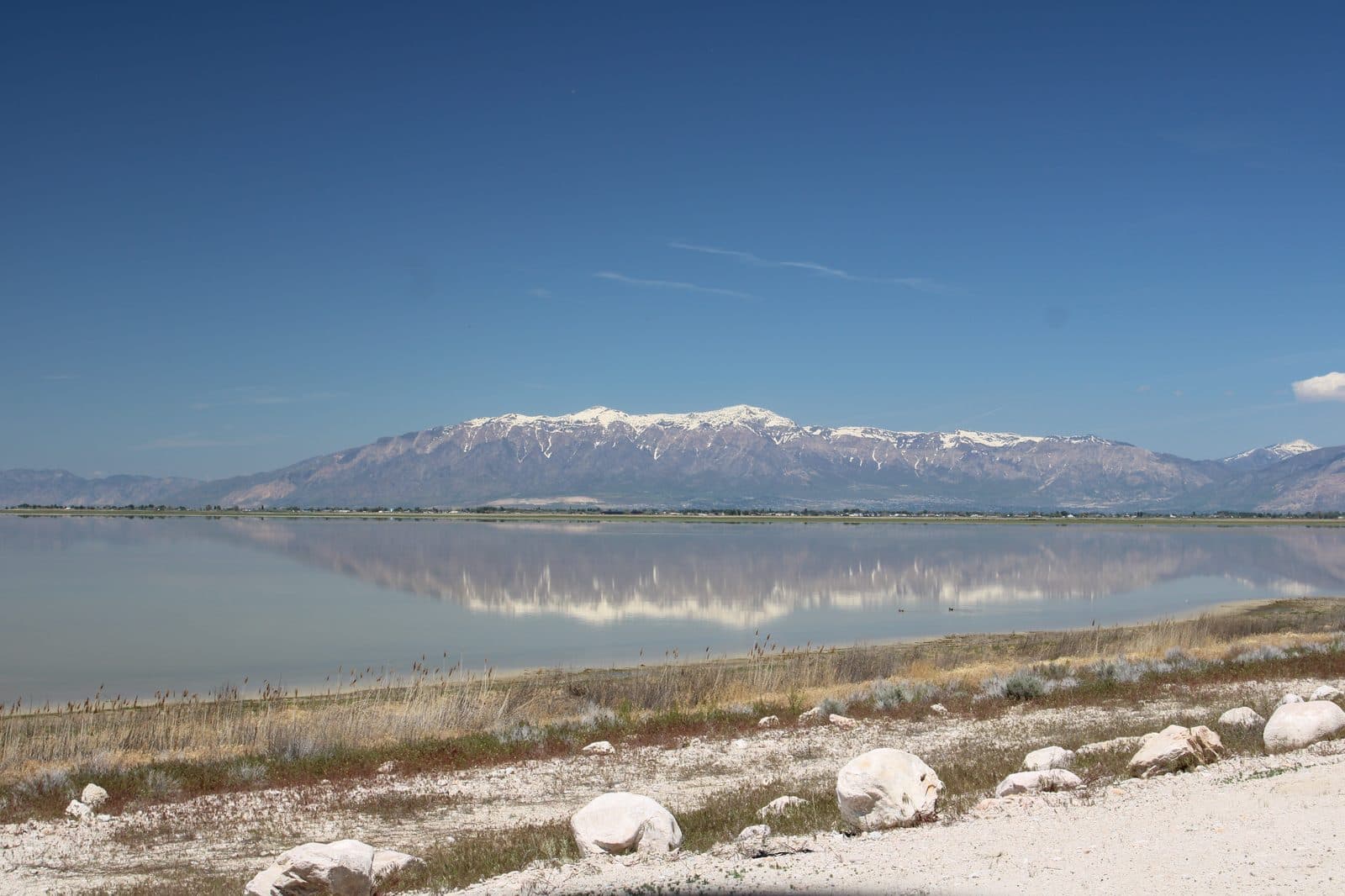 The Wellsville Mountains with snow on the peaks, reflected in still water.